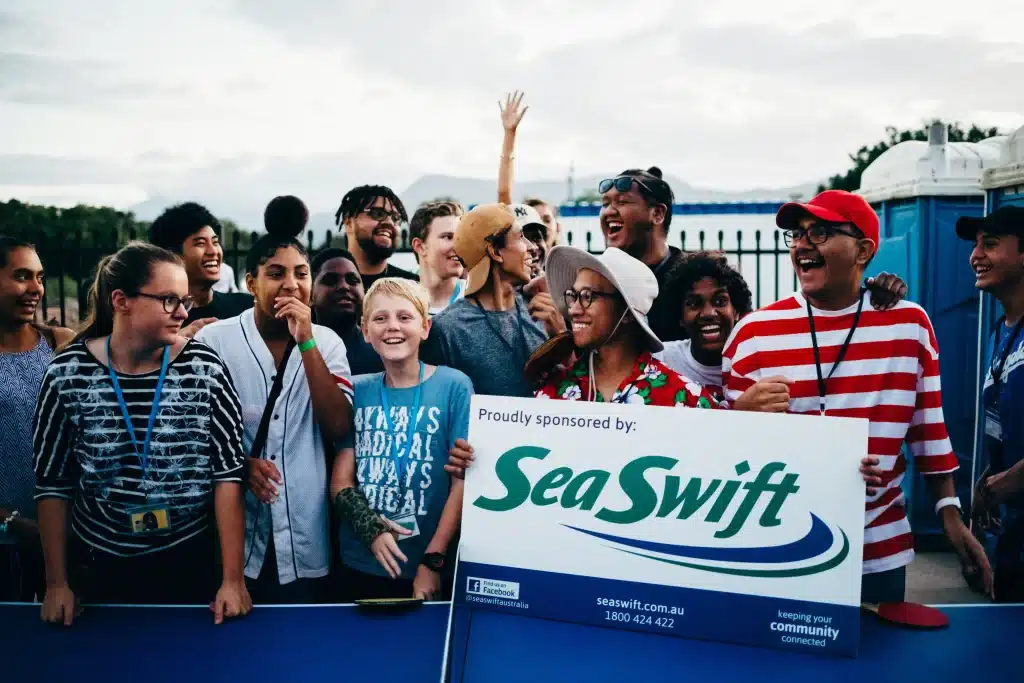 A group shot with a person holding a sign that says "Proudly sponsored by: Sea Swift".